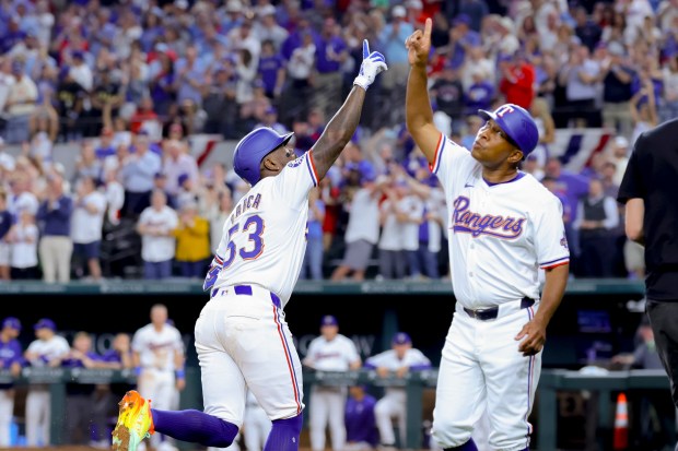 Texas Rangers' Adolis Garcia (53) and third base coach Tony Beasley, right, celebrate Garcia's home run during the sixth inning of the team's baseball game against the Chicago Cubs, Thursday, March 28, 2024 in Arlington, Texas. (AP Photo/Gareth Patterson)