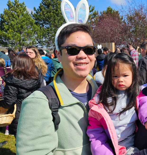 Chris Moy of Naperville and his 2-year-old daughter Callie were among the first to rush out and gather eggs on the field north of Faith Lutheran Church in Aurora Saturday morning during the church's annual Easter egg hunt. (David Sharos / For The Beacon-News)