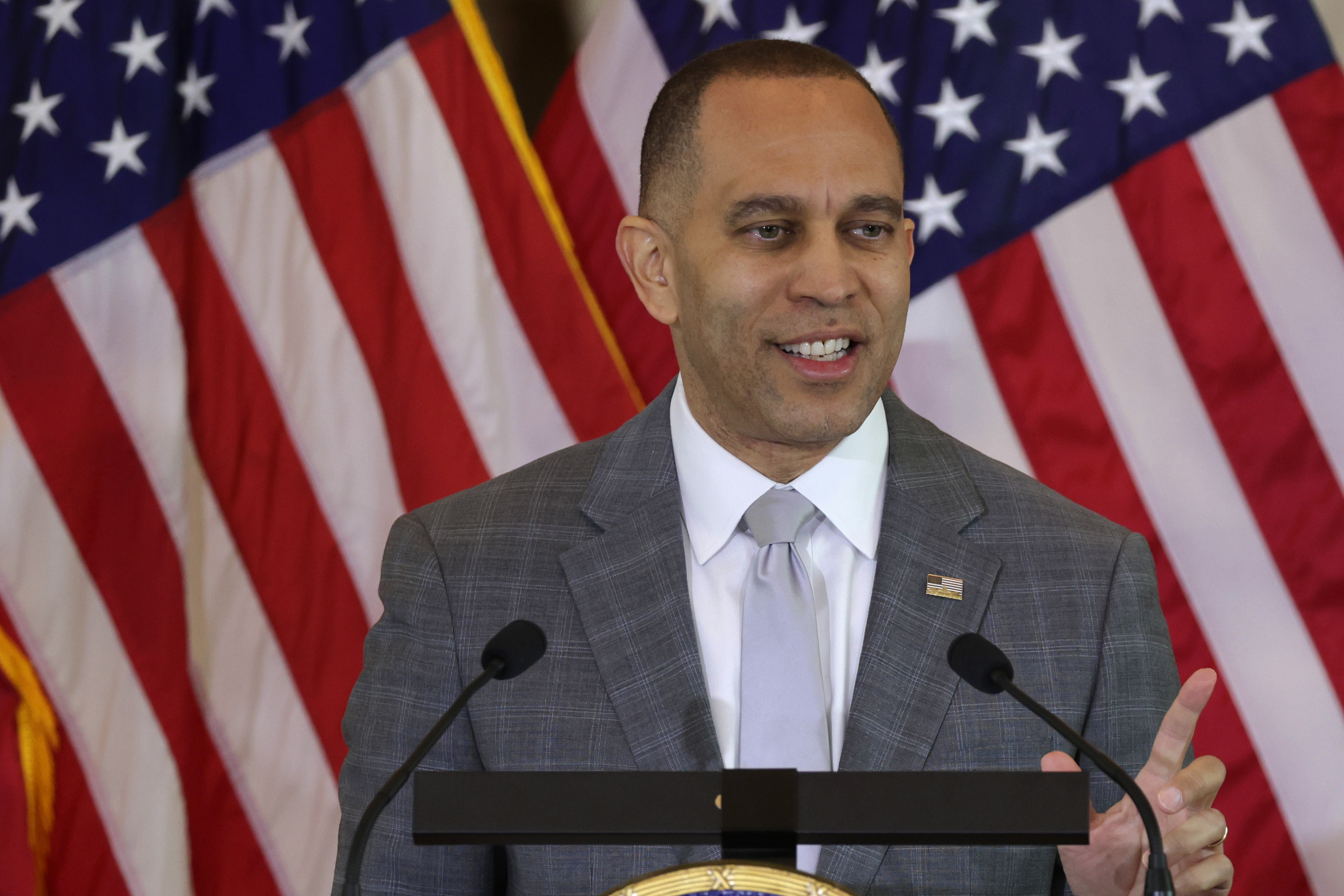 Hakeem Jeffries speaks at a podium in front of American flags.