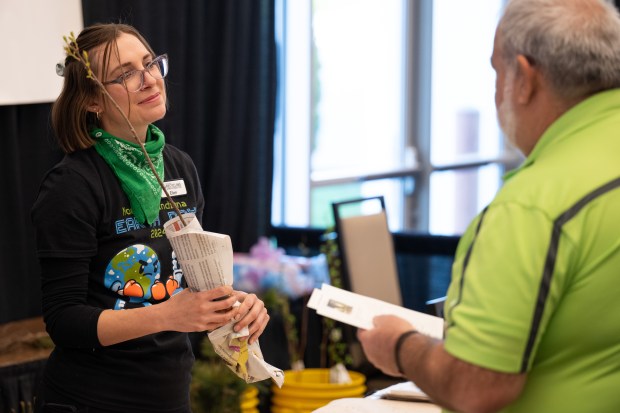 Ellen Kapitan, with Porter County Recycling and Waste Reduction, hands a chokecherry sapling to Junkluggers employee Lou Macaluso during the 16th annual Recycling and Waste Reduction District of Porter County Earth Day Program on Saturday, April 20, 2024. (Kyle Telechan/for the Post-Tribune)