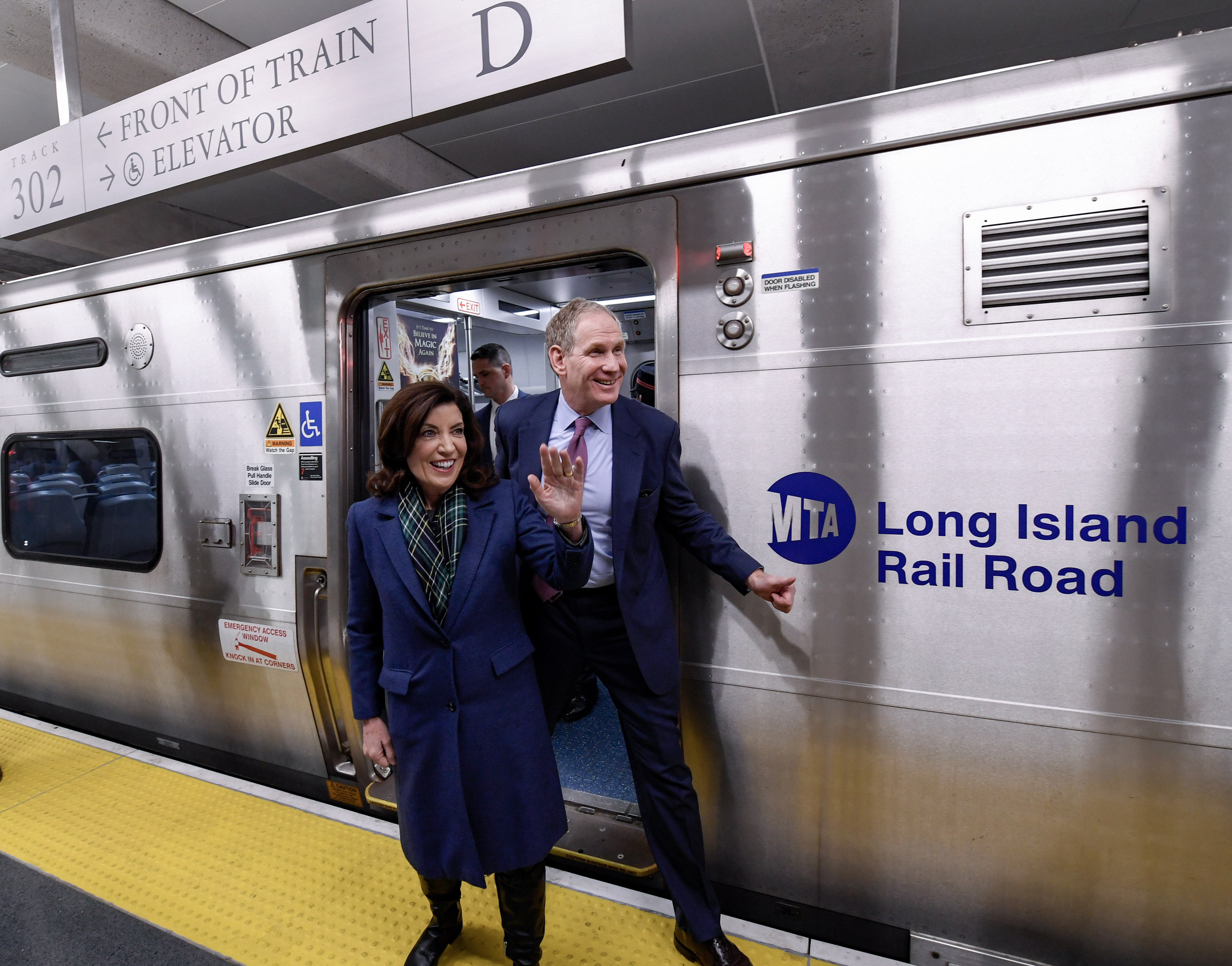 Two government officials smiling at the opening of a long delayed train station.