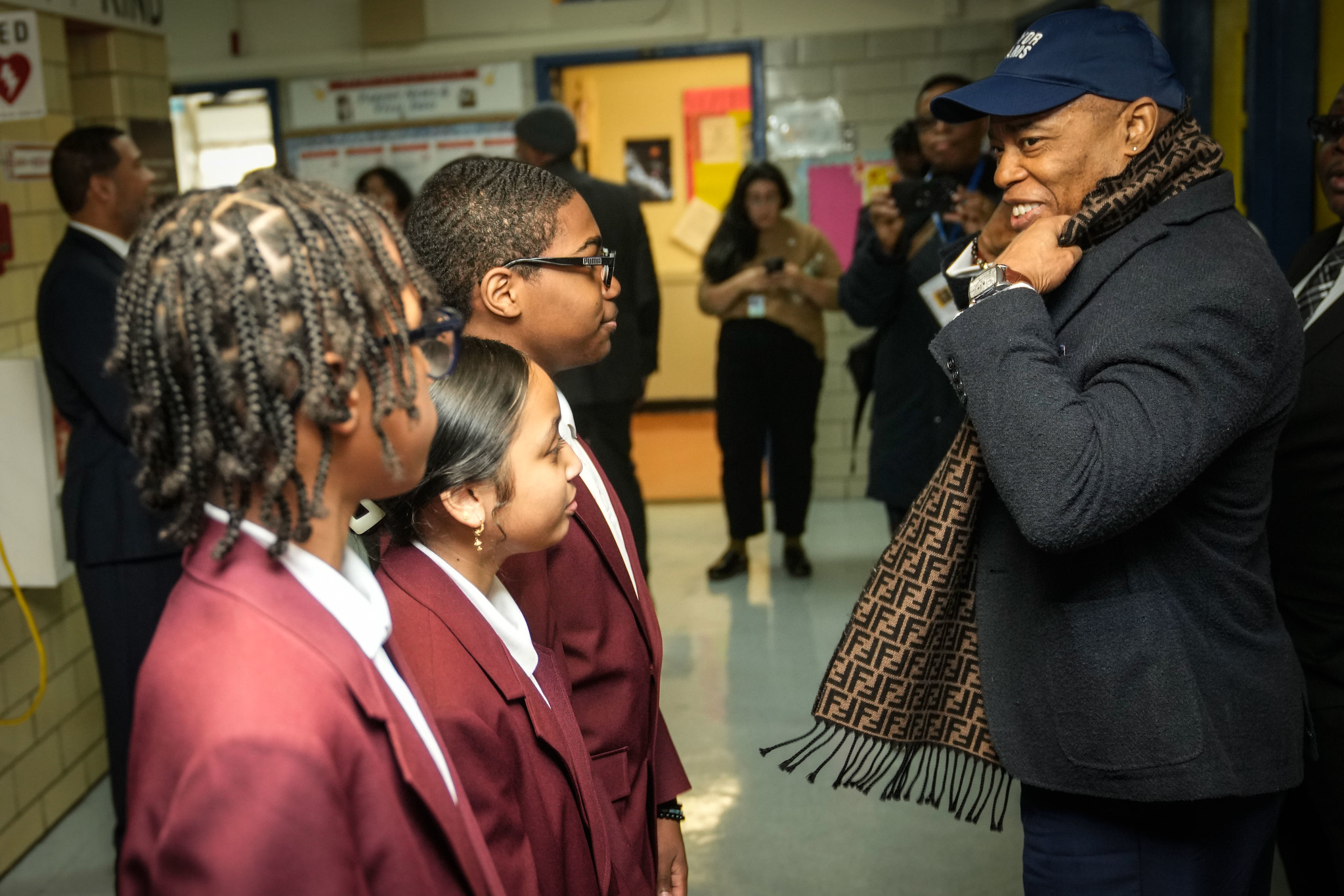 Mayor Eric Adams smiles at a trio of students.