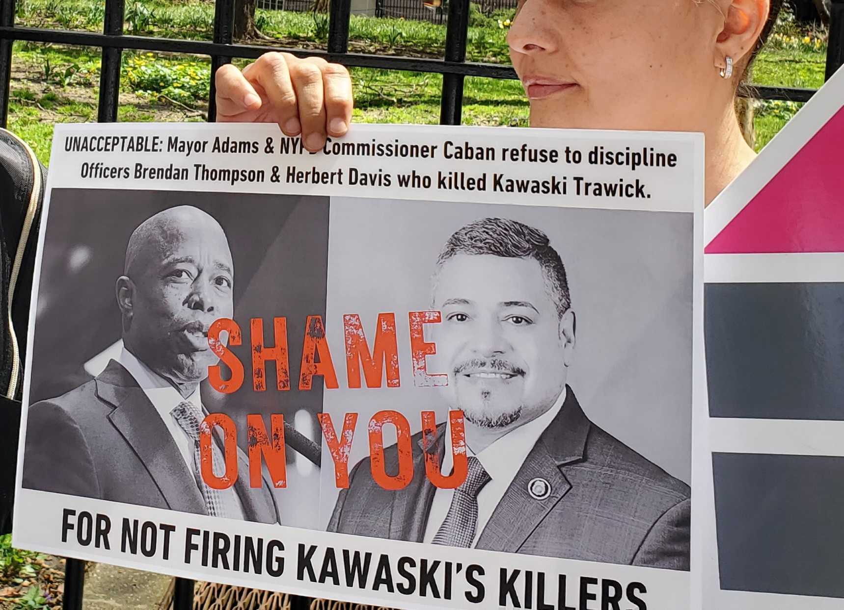 Advocates hold signs depicting Mayor Eric Adams and Caban, stamped with the words, “Shame on you for not firing Kawaski’s killers."