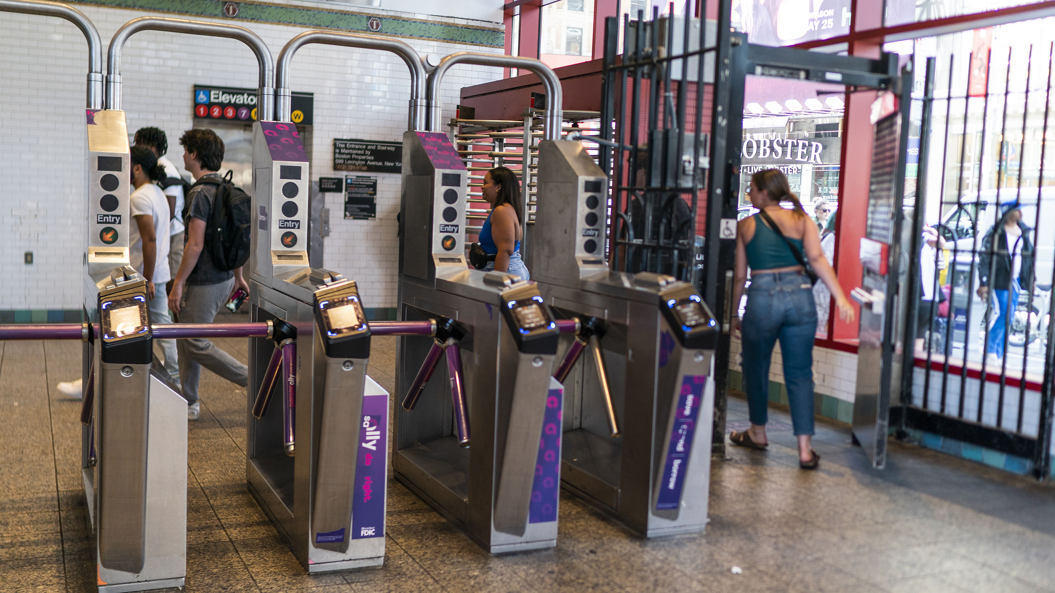 Riders in New York City avoiding the subway fare by going through an emergency gate.