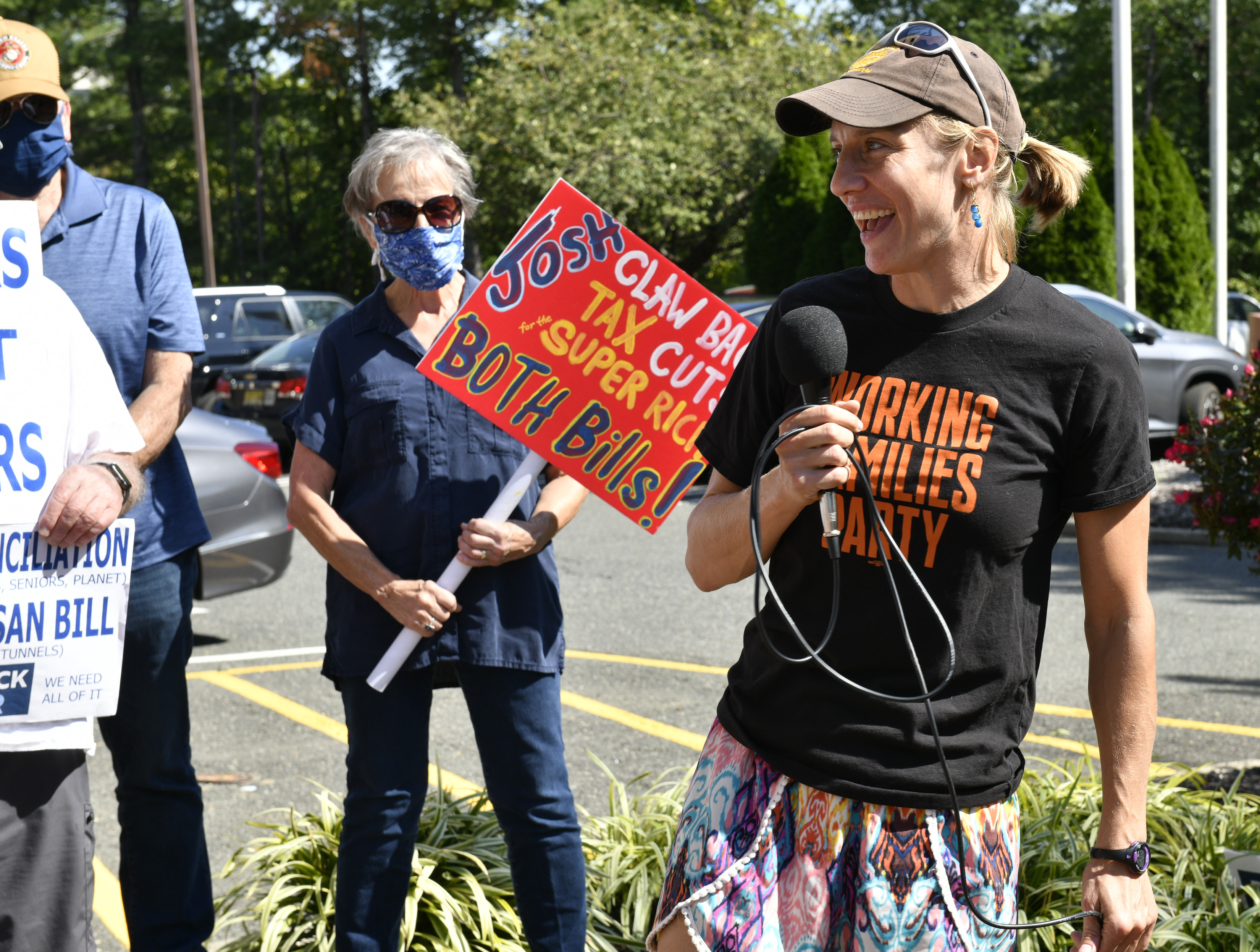 Activists protest at the office of Rep. Josh Gottheimer. One carries a sign saying "claw back tax cuts for the super rich."