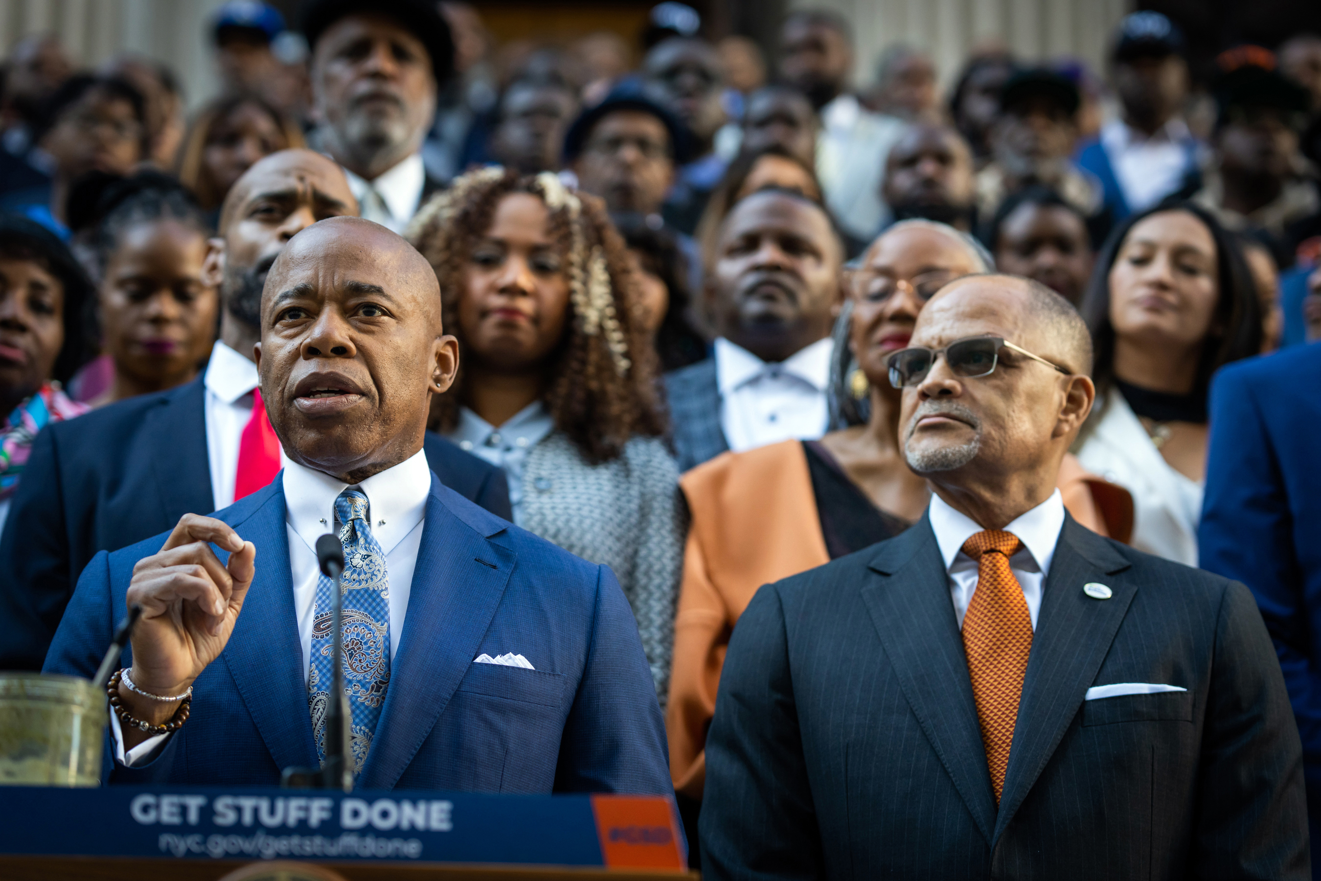 Mayor Eric Adams speaks at a podium, flanked by Schools Chancellor David Banks.