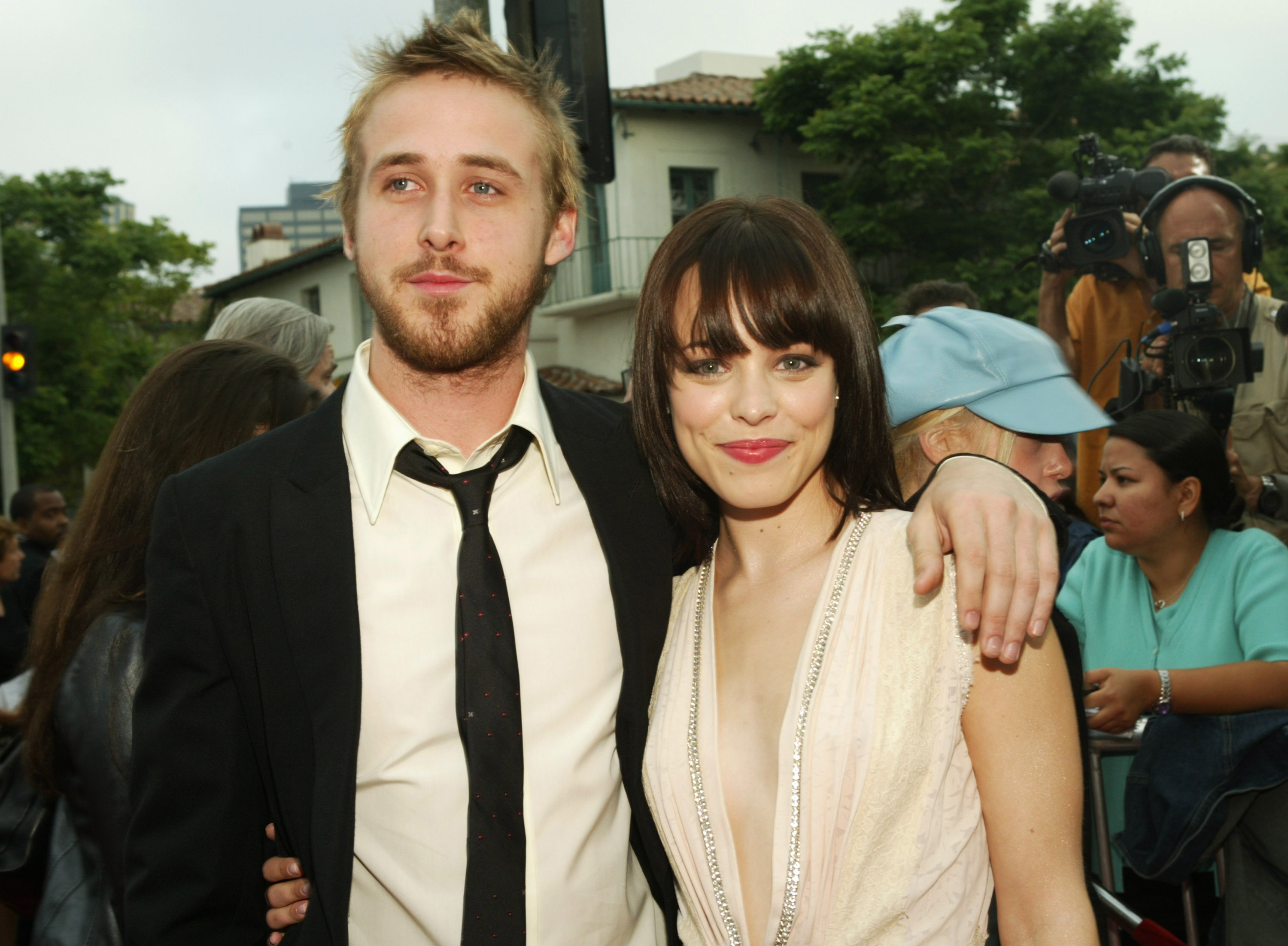 A man in a suit drapes his arm over a woman in a white dress.