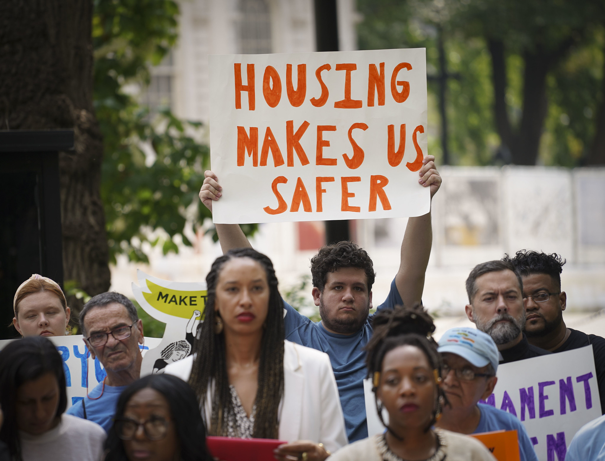 Demonstrators hold signs and wear bright shirts in favor of stronger housing protections.