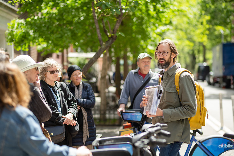 A man stands in front of a tour group while giving a walk.