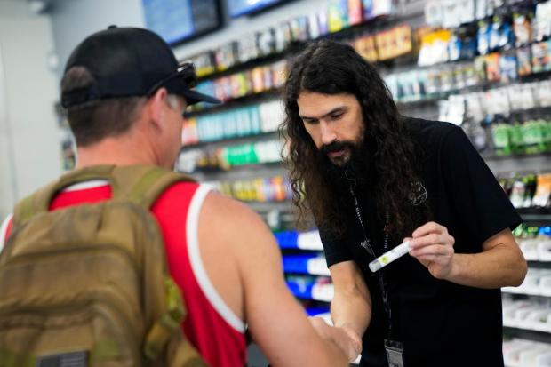 Cloud 9 Cannabis employee Beau McQueen, right, helps a customer, Saturday, April 13, 2024, in Arlington, Wash. The shop is one of the first dispensaries to open under the Washington Liquor and Cannabis Board's social equity program, established in efforts to remedy some of the disproportionate effects marijuana prohibition had on communities of color. (AP Photo/Lindsey Wasson)