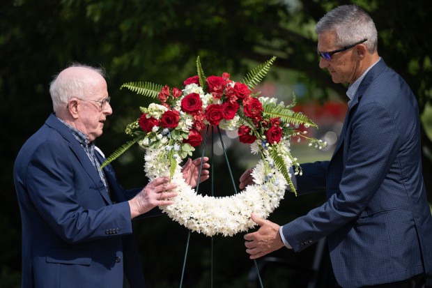 Valparaiso Mayor Jon Costas, on right, and Army veteran Robert Shankland pick up a wreath to be placed on the Valparaiso war memorial during the city's Memorial Day service on Friday, May 24, 2024. (Kyle Telechan/for the Post-Tribune)