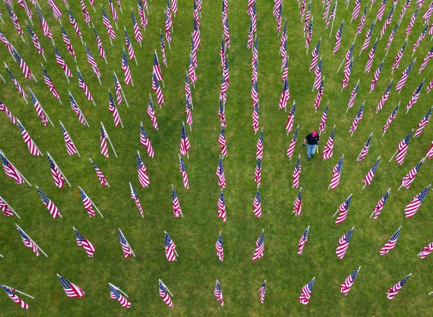 Vietnam veteran Clyde Gendreau, 68, straightens an American flag at Randall Oaks Park on May 24, 2024, in West Dundee. Over 1,500 flags represent service members still missing in action in the Vietnam War. Gendreau is a U.S. Air Force veteran who served in Vietnam as a weapons mechanic. (Stacey Wescott/Chicago Tribune)