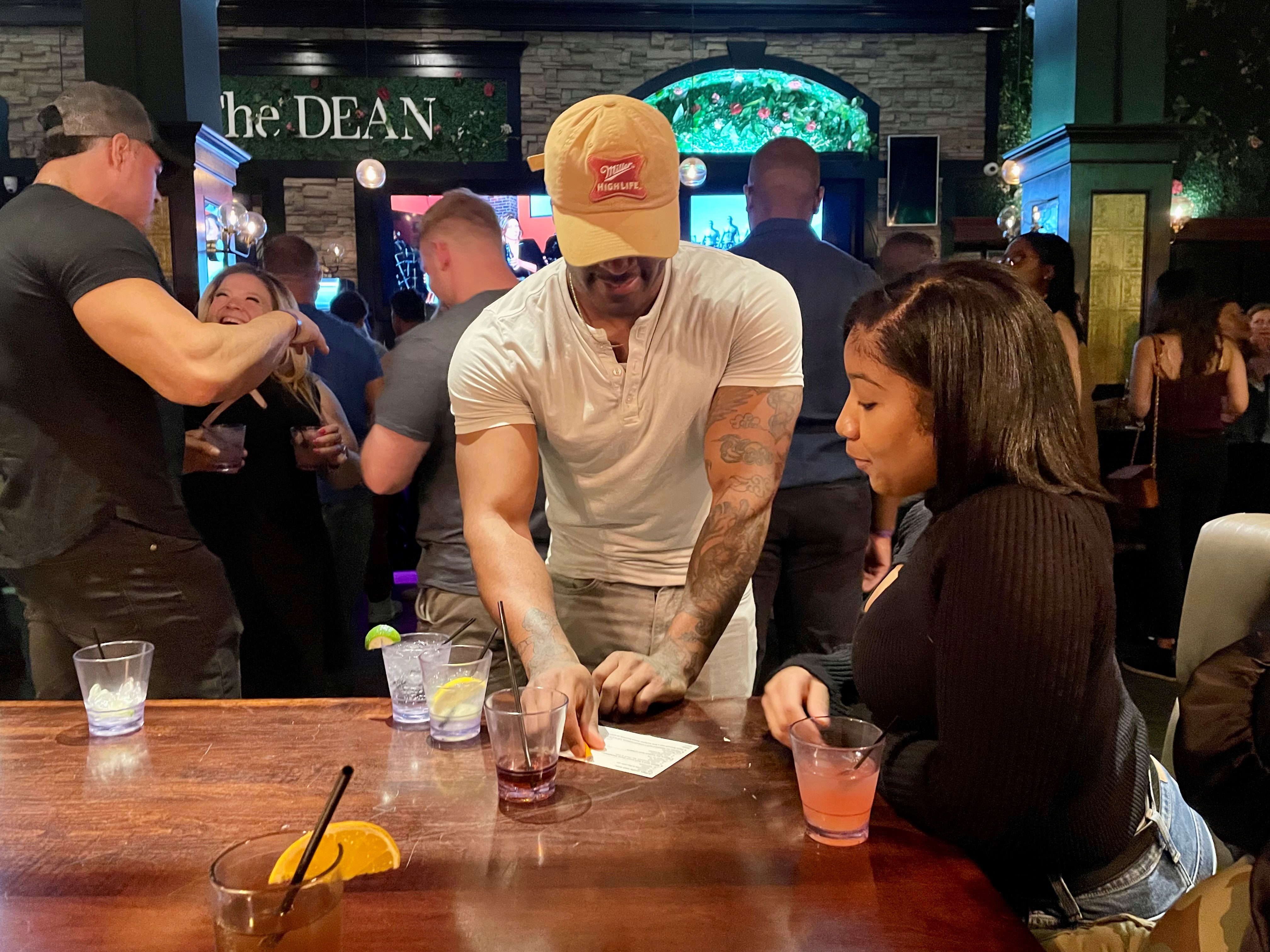 A group of people talk around a table at a bar.