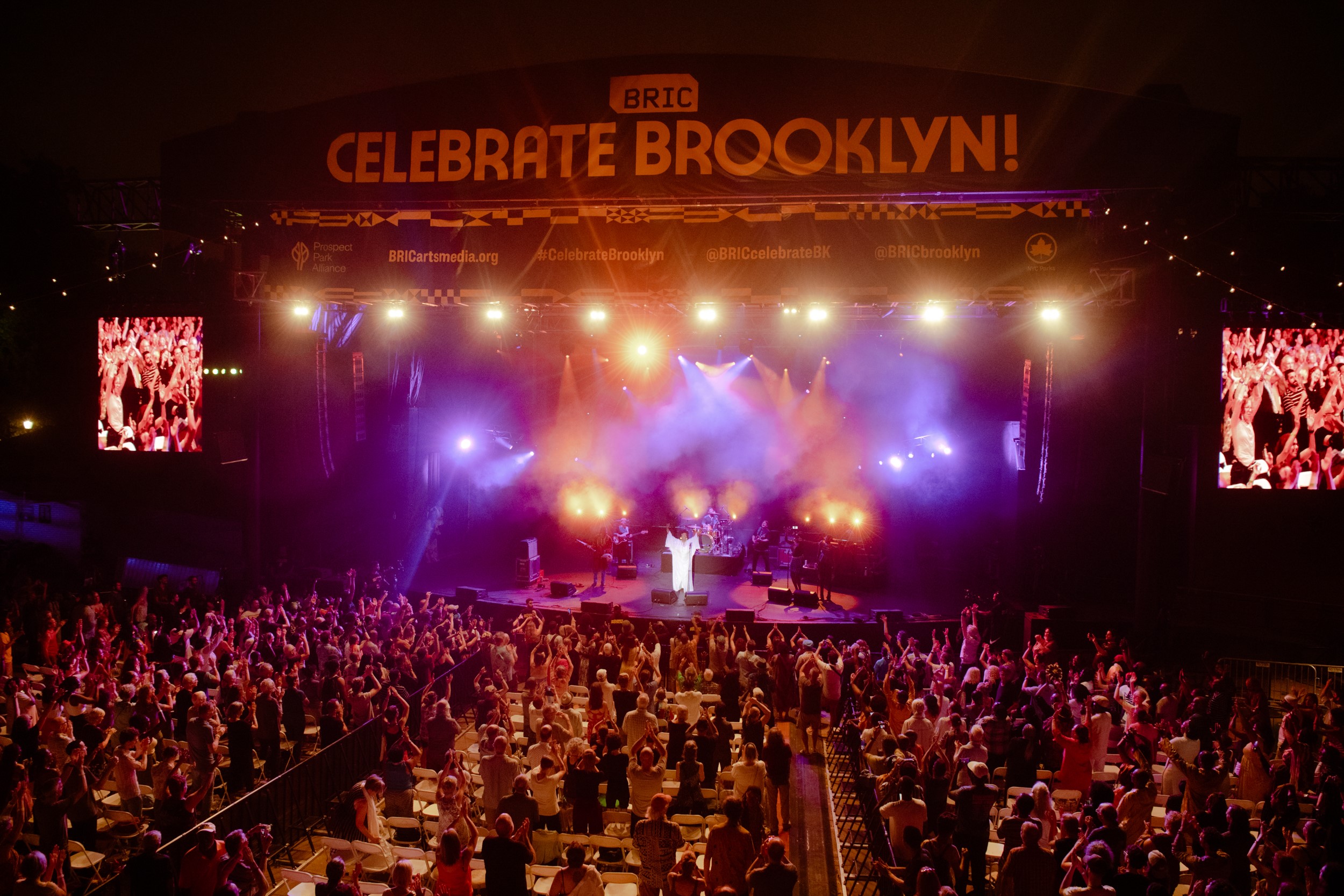 A crowd of people cheers in front of a stage