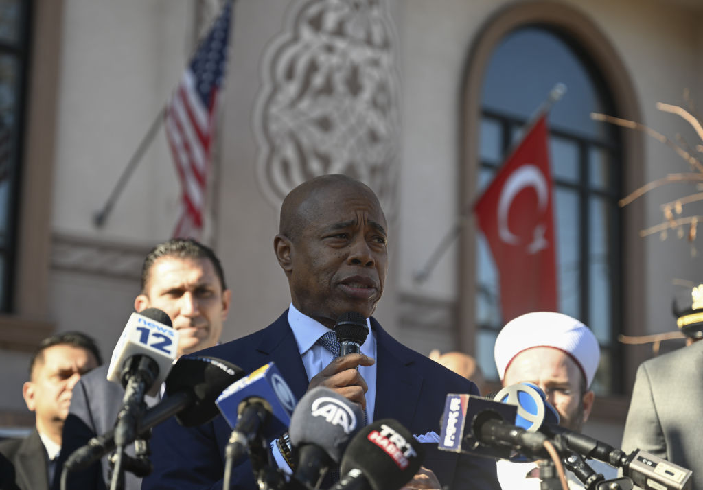 Mayor Adams speaking in front of a mosque with the Turkish flag