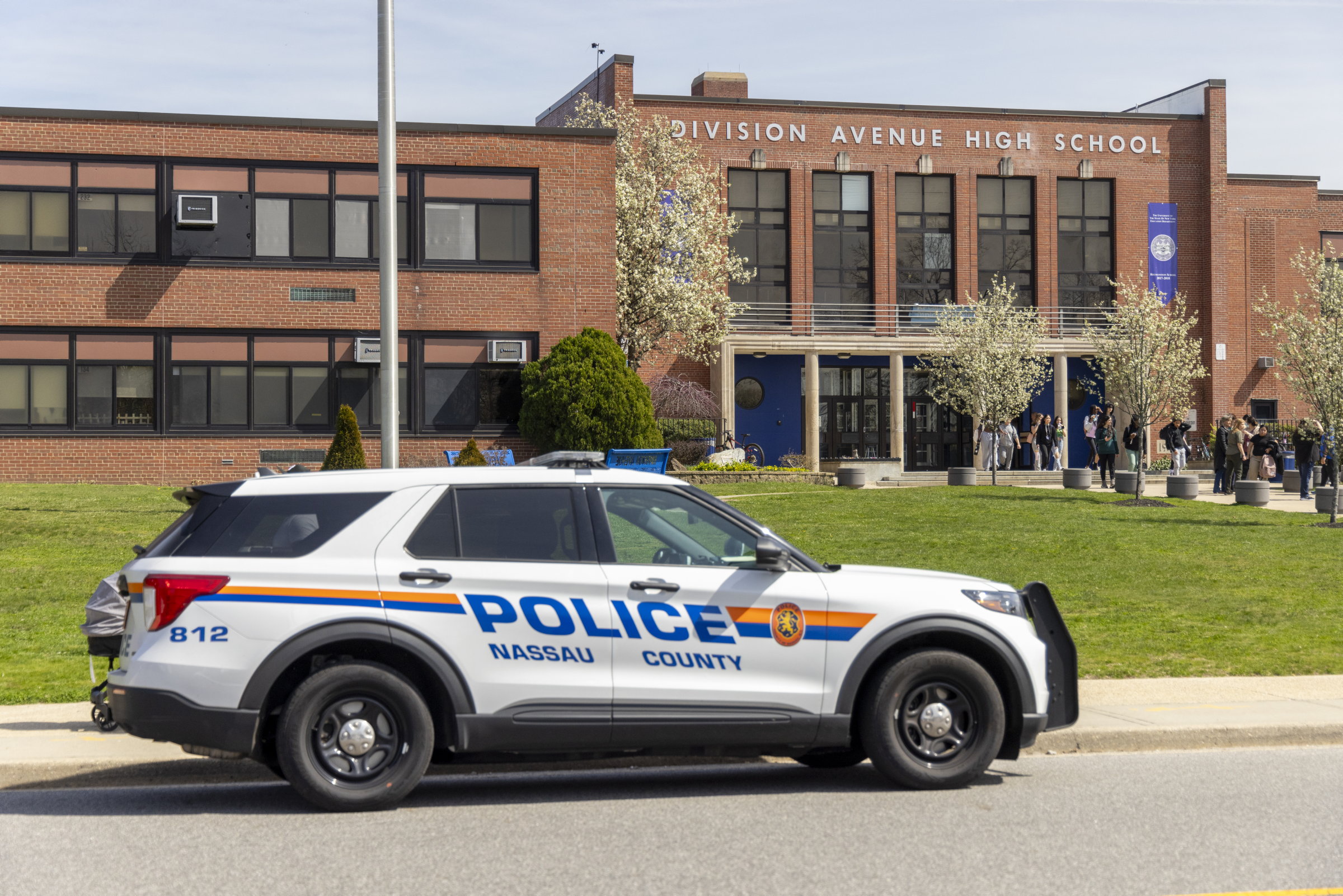 A Nassau County police car is parked outside of a school.