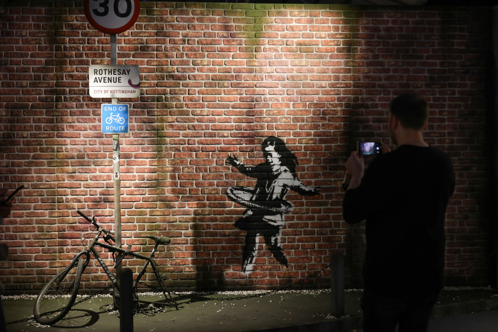 A man takes a photo of Banksy's "Hula-Hoop Girl" at an exhibit in Cologne, Germany, May 9, 2024.