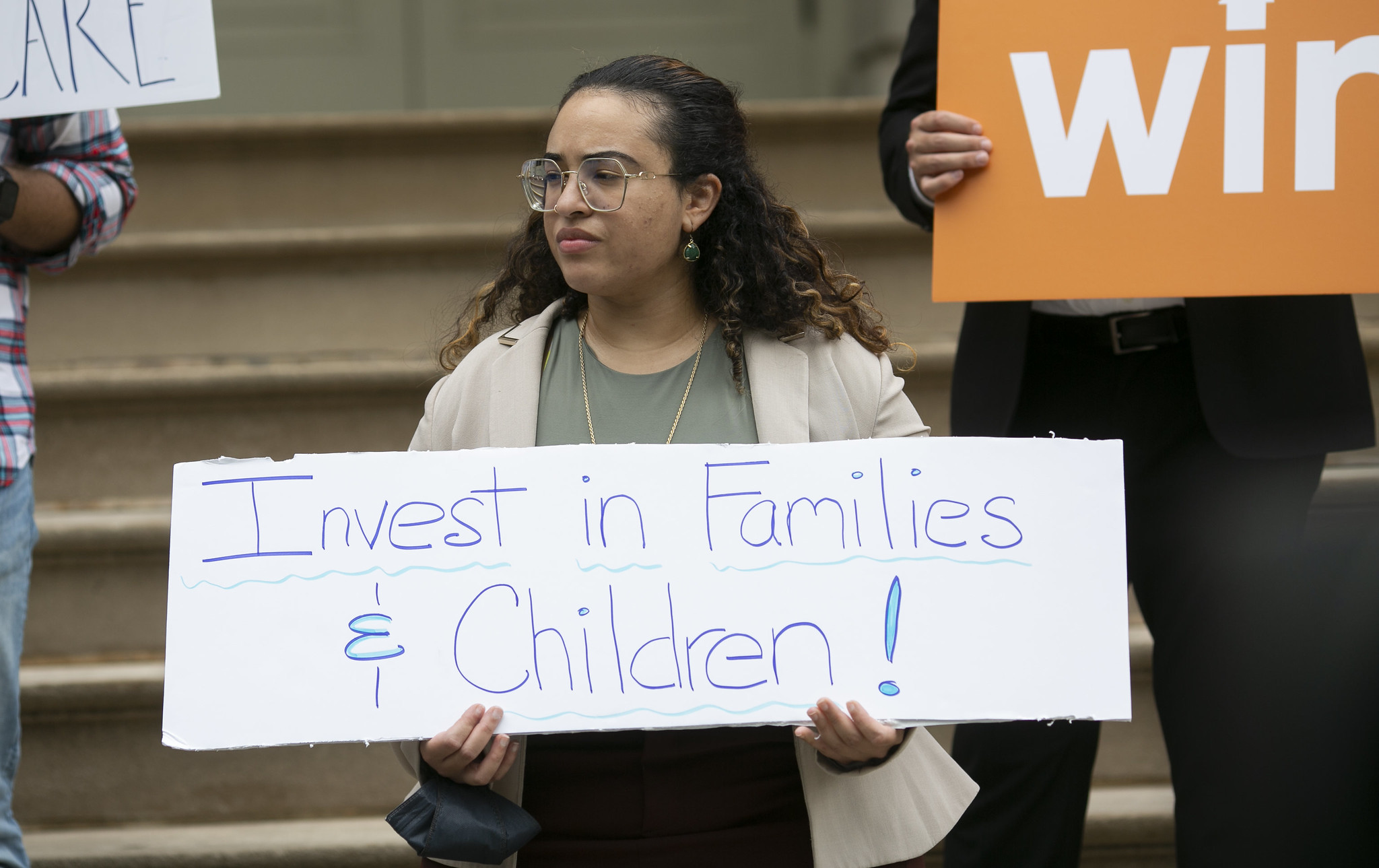 A demonstrator holding a sign saying "invest in families and children."