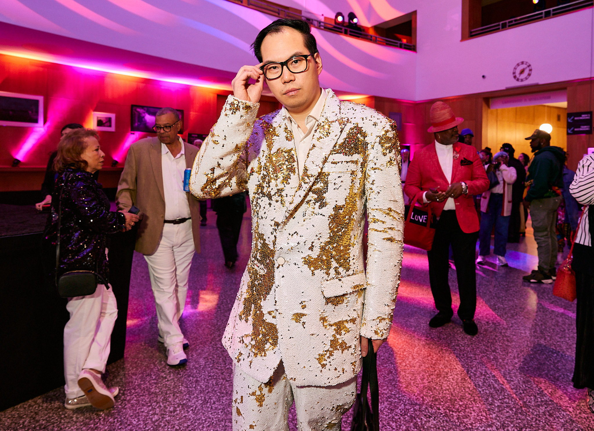 A man poses in a white suit.