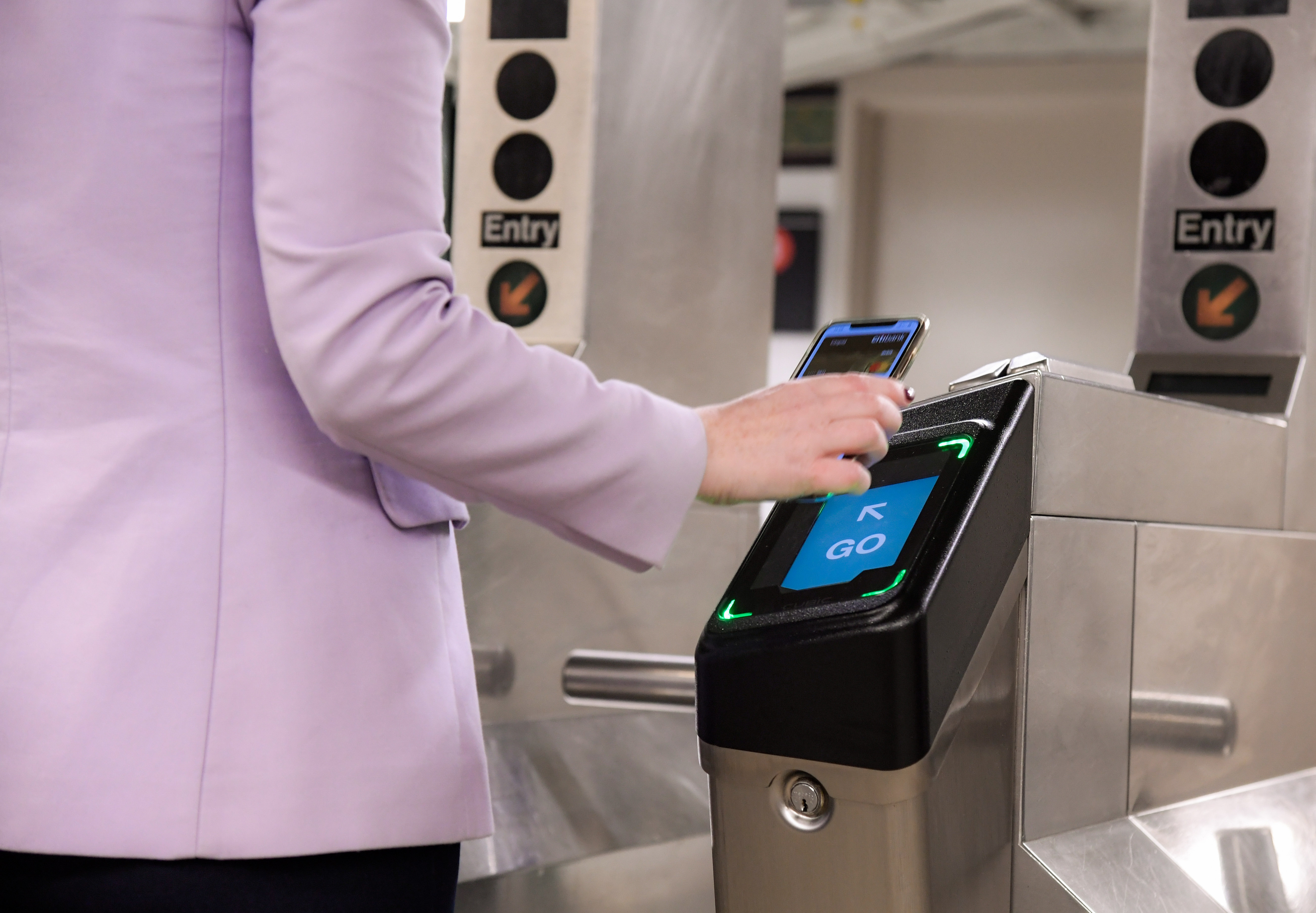 A person uses a smartphone at an MTA turnstile.