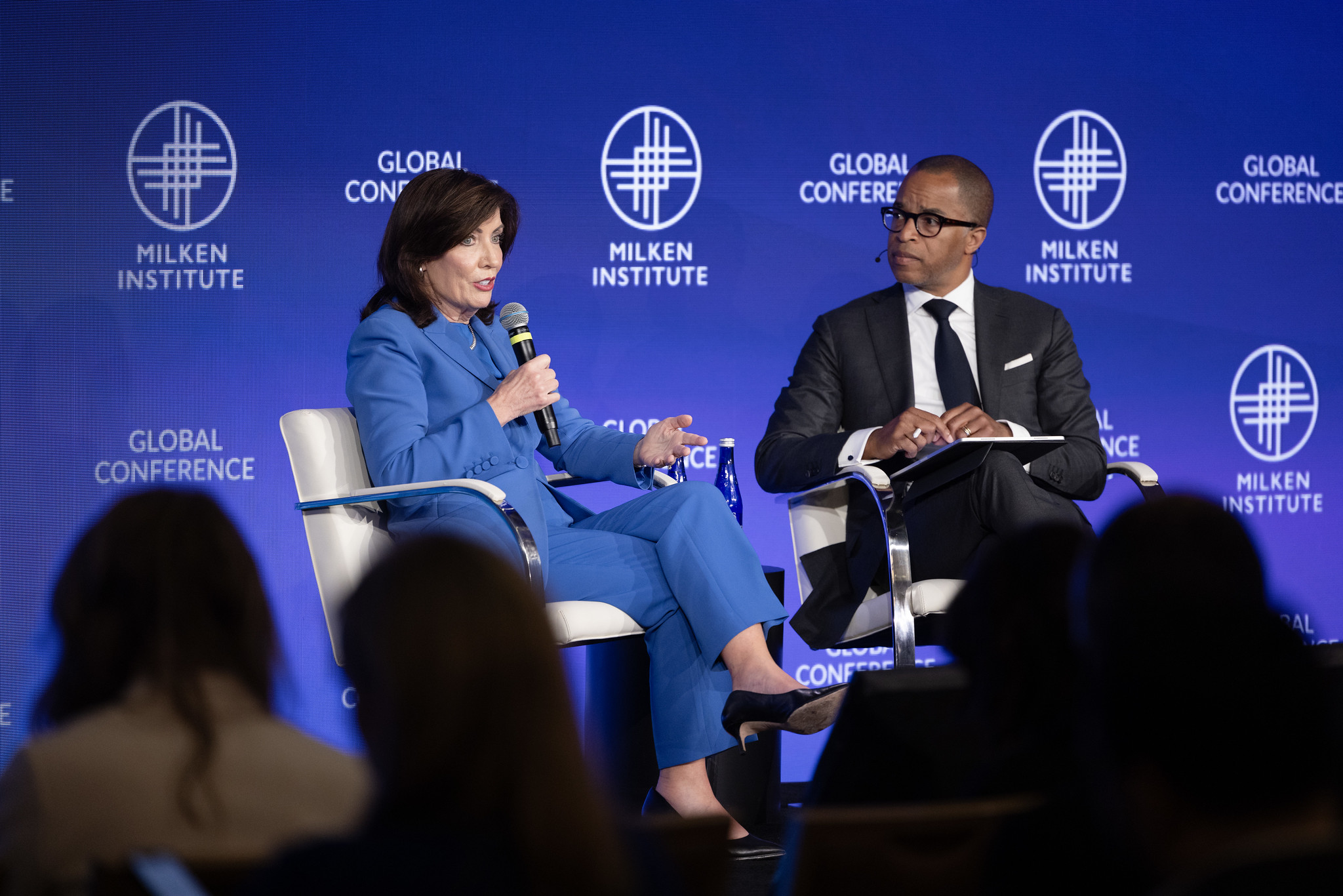 Gov. Kathy Hochul, in a blue suit, sits next to MSNBC's Jonathan Capehart on stage at a conference.