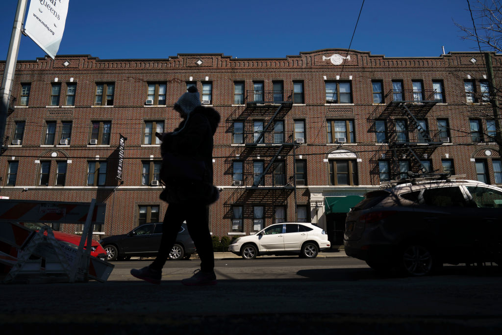 A person walks in front of an apartment complex in Astoria.