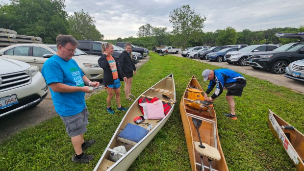 Joe Welsh of North Aurora, left, gets ready to bring a borrowed canoe to a launch point in Geneva on Saturday for the 59th Mid-America Canoe and Kayak Race on the Fox River. (David Sharos / For The Beacon-News)