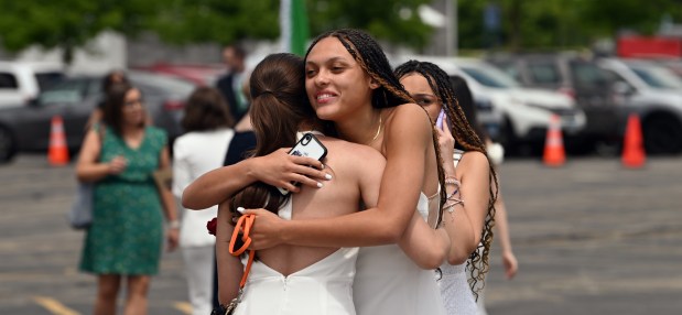 Right, facing, in a hug moment is Norah Clarke of Wilmette before the 124th annual New Trier Township High School commencement on June 2, 2024 at NOW Arena in Hoffman Estates. (Karie Angell Luc/Pioneer Press)