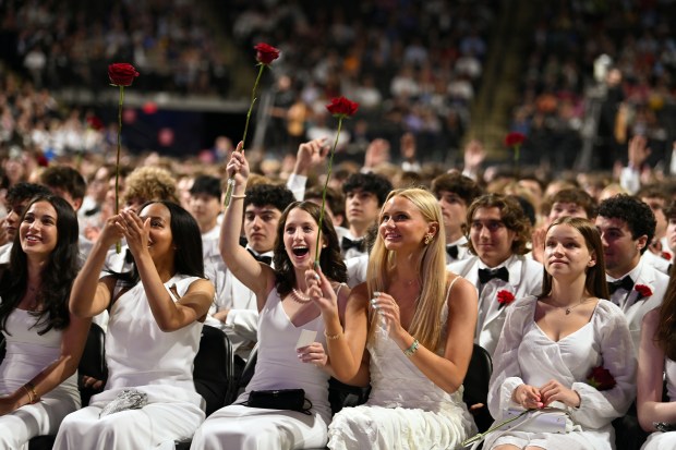 Second from the right, front row, holding up a rose is Claire Houlihan of Wilmette at the 124th annual New Trier Township High School commencement on June 2, 2024 at NOW Arena in Hoffman Estates. (Karie Angell Luc/Pioneer Press)