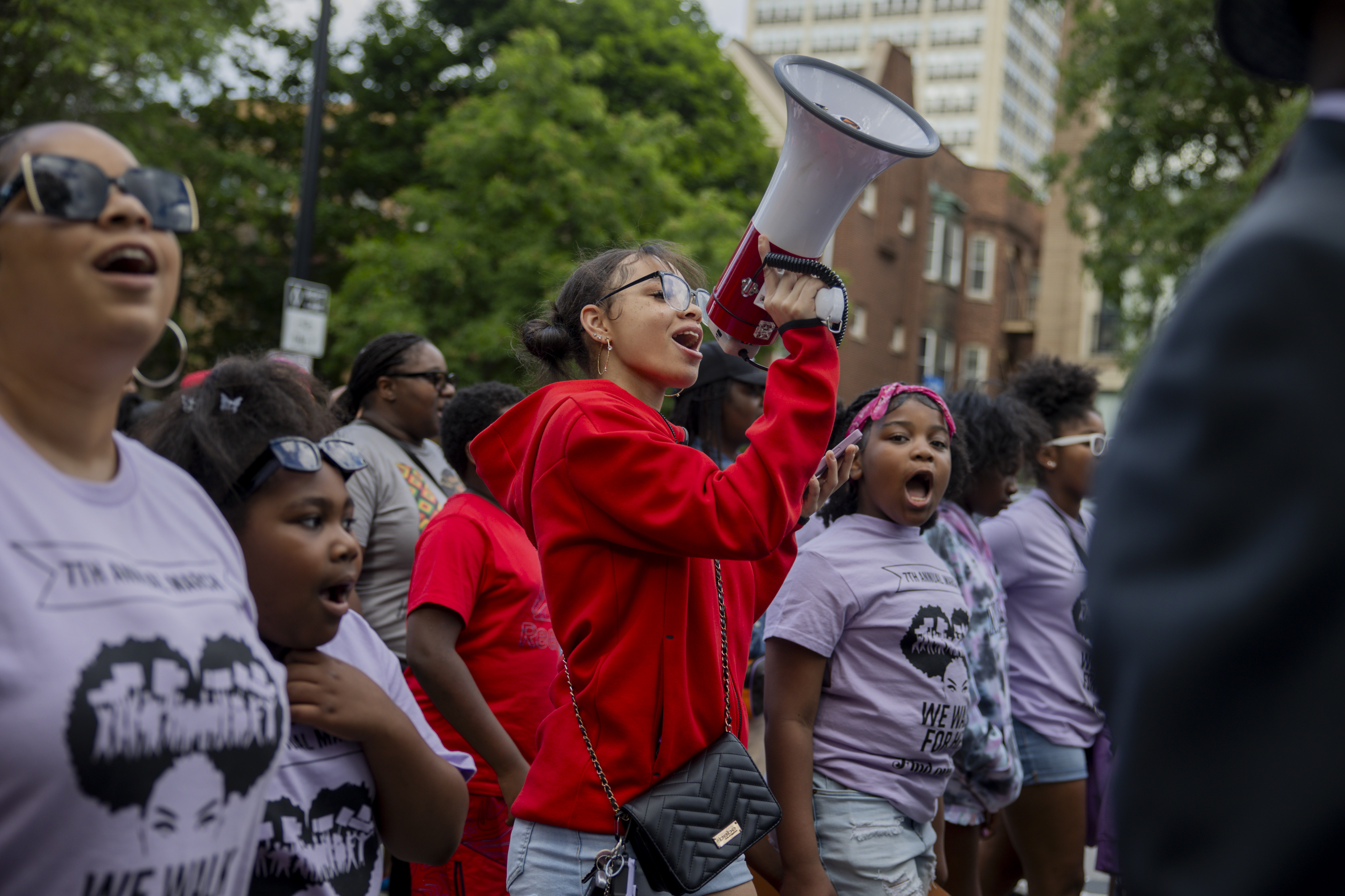 Kyla, a young activist, leads a chant as community members...