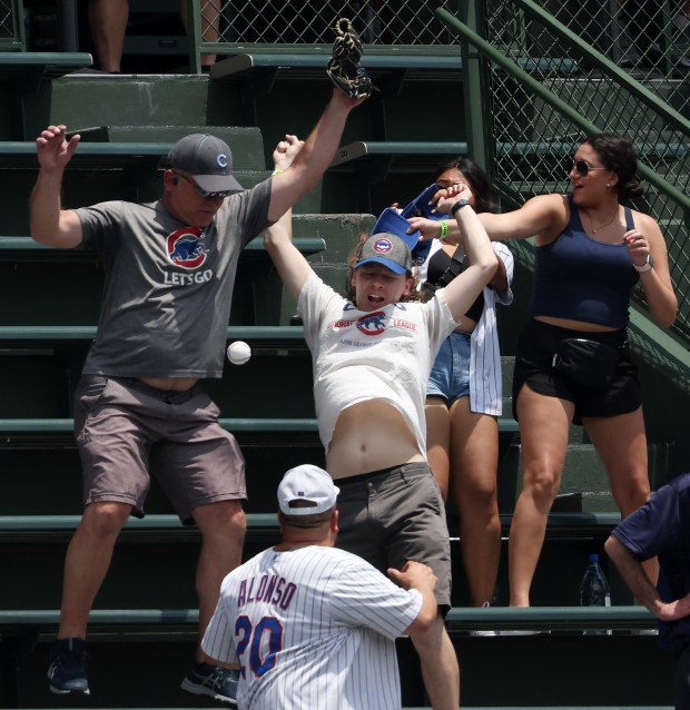 Fans reach for a batting practice home run ball before a game between the Cubs and Mets at Wrigley Field on June 22, 2024, in Chicago. (John J. Kim/Chicago Tribune)