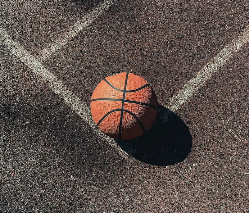 A basketball laying on an outdoor court.