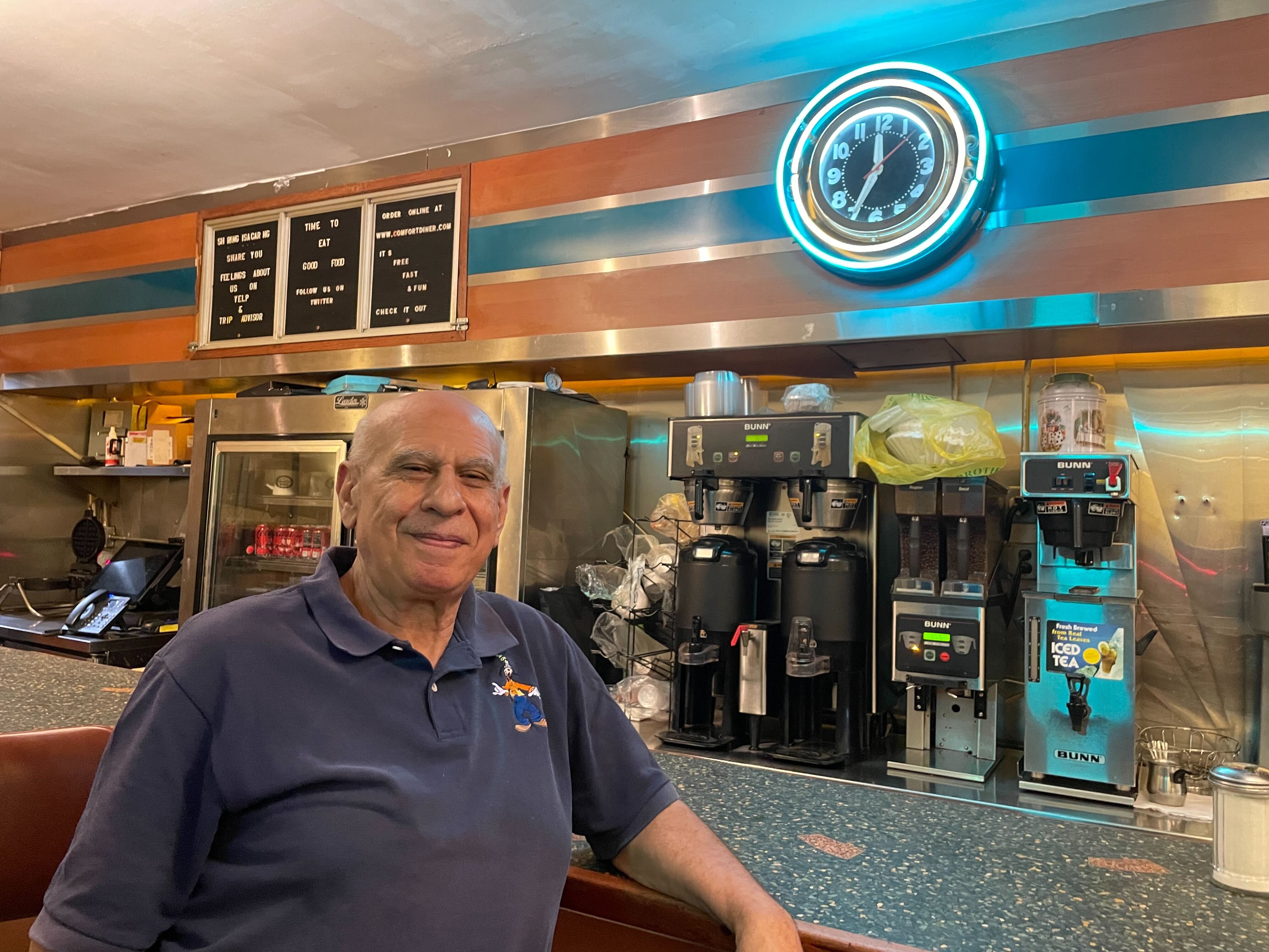 A smiling man sits at a diner counter.