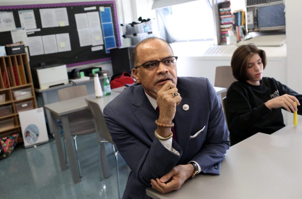 Schools Chancellor David Banks sits at a classroom desk.