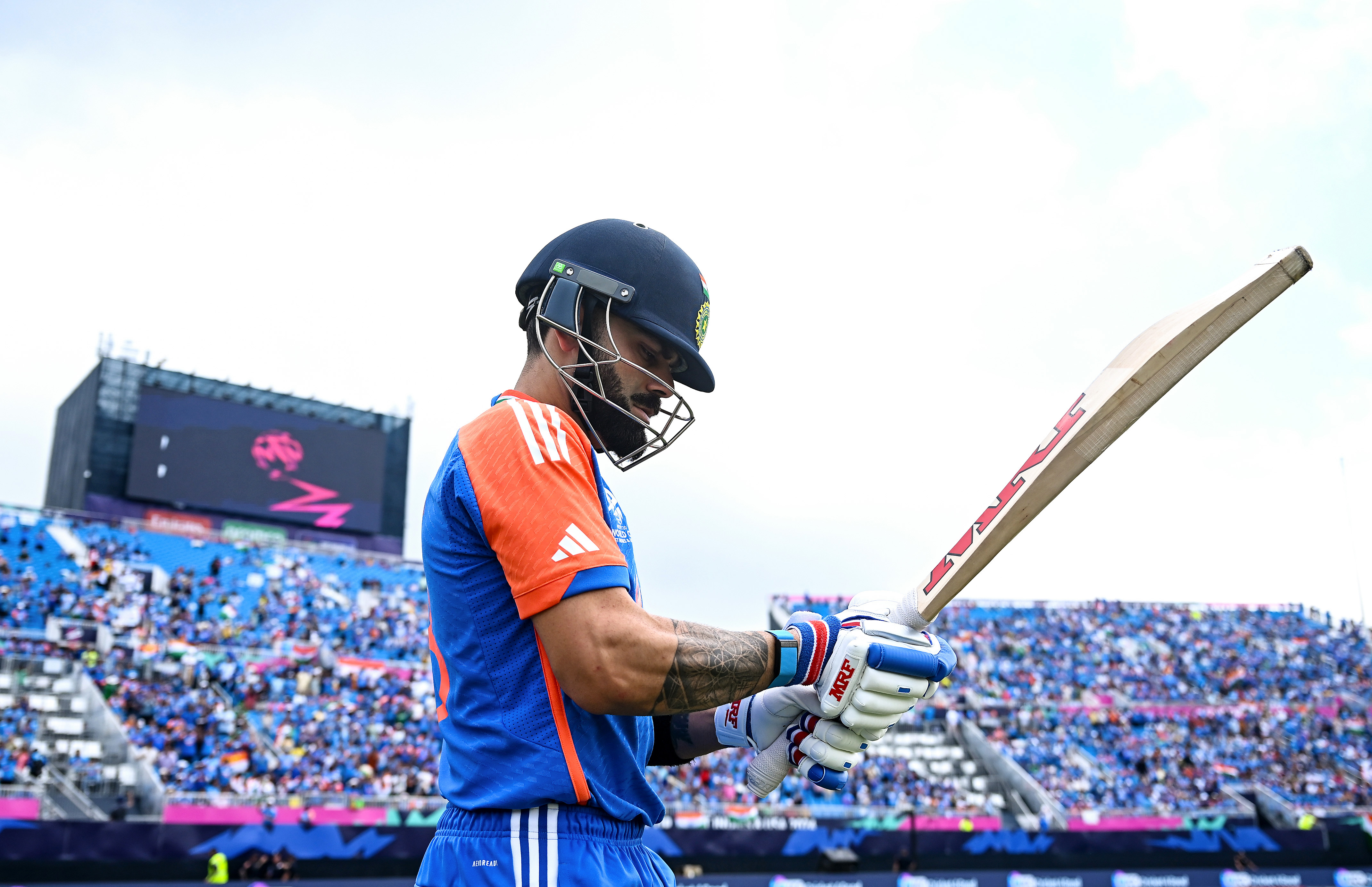 A cricket player holds a bat.