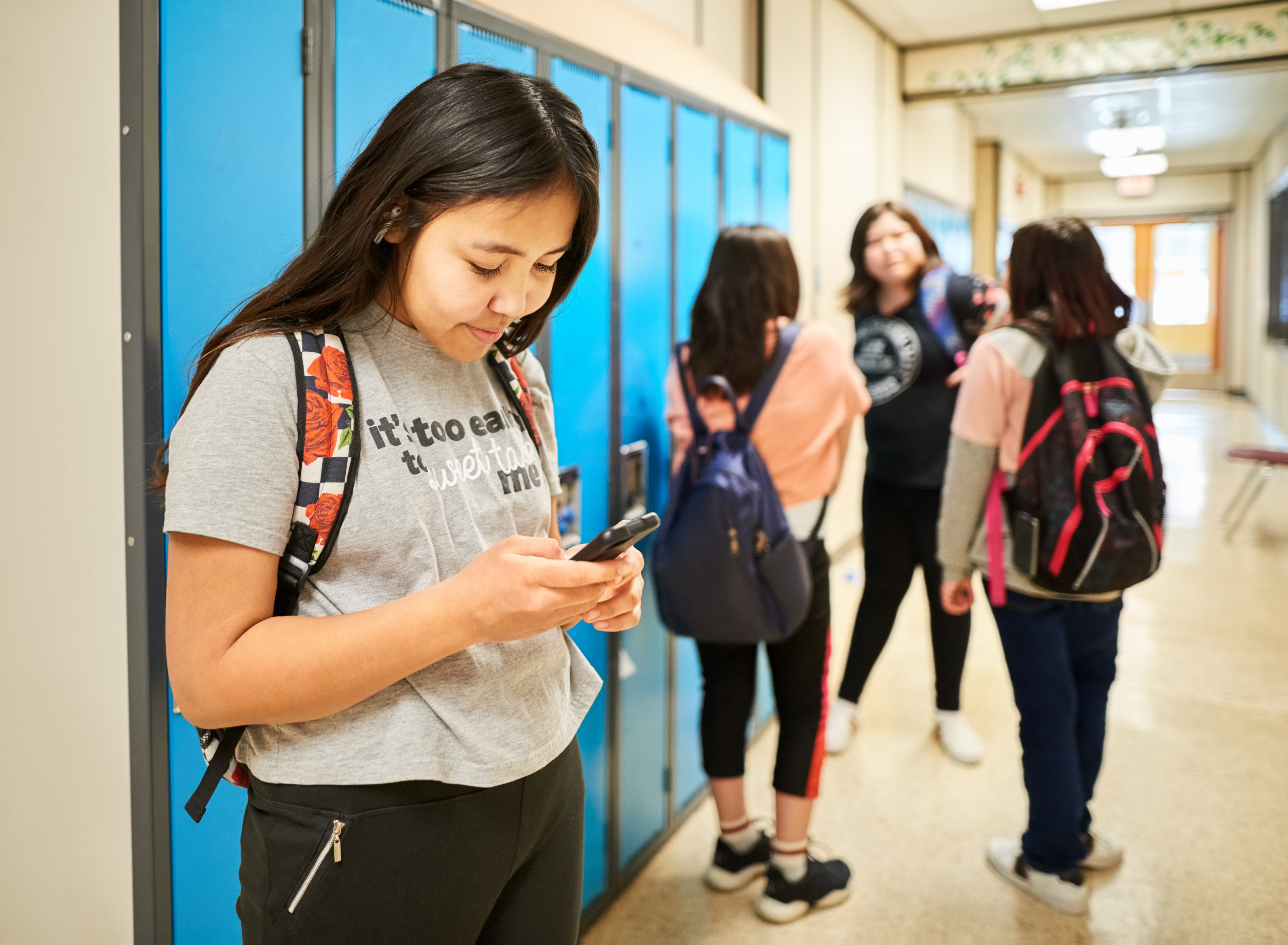 A girl using her smartphone at a school locker.