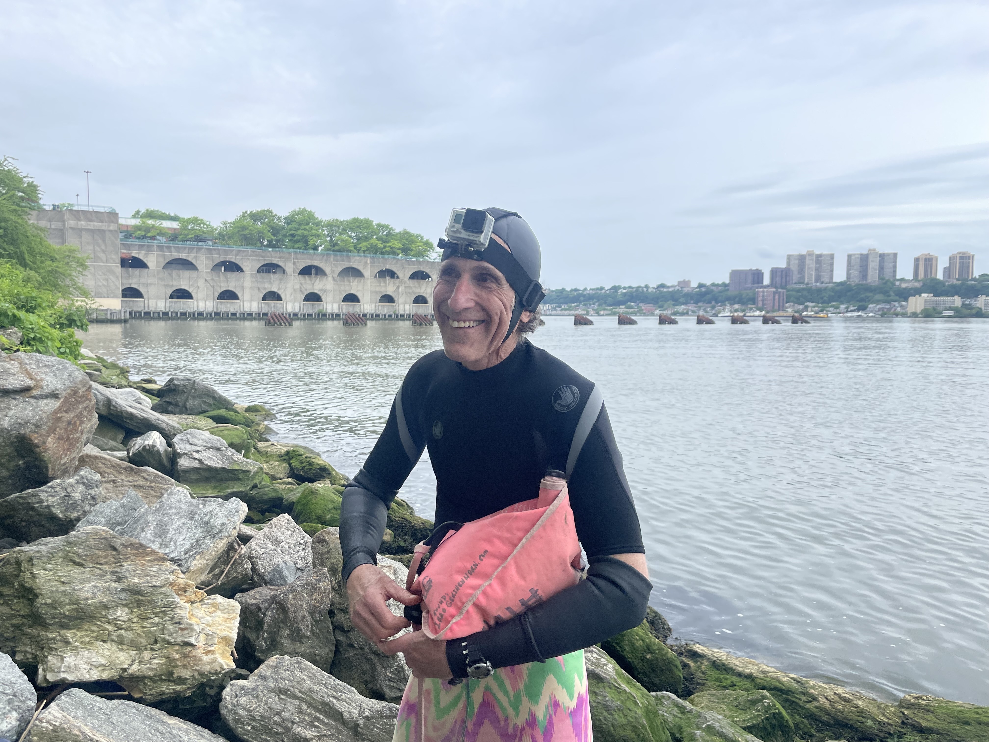 A man standing in front of the Hudson River, where he swims once a week.